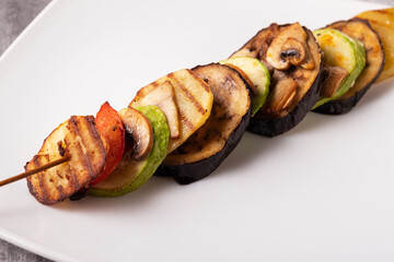 Grilled vegetable ratatouille on a white plate and gray background. Horizontal orientation, no...