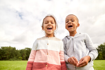 childhood, leisure and people concept - happy smiling little boy and girl at park