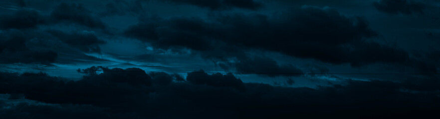 Black blue night sky with clouds. Dark teal skies background with copy space for design. Wide...