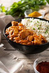 Indian butter chicken in black bowl on wooden table