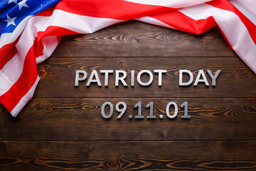 the words patriot day laid with silver metal letters on wooden board surface with crumpled usa flag