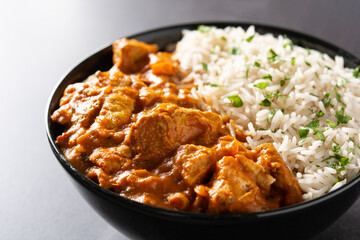 Indian butter chicken in black bowl on black background. Close up