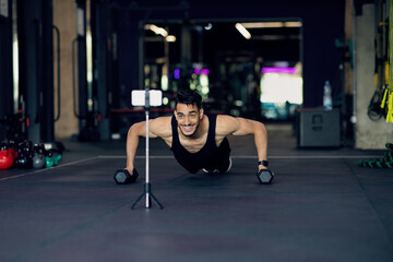 Obraz na płótnie Canvas Athletic Arab Man Making Dumbbell Push-Ups While Recording Content On Smartphone Camera