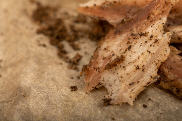 thinly sliced homemade lard with pepper on white oiled paper, close-up, selective focus.