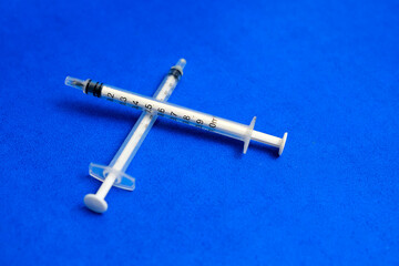 A pair of syringes on a blue background