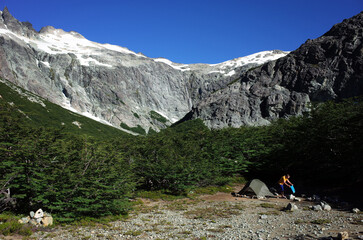 Camping tent in Andes, Argentina hiking trail, Trekking in Patagonia Nahuel Huapi National Park, Man tourist next to green tent at bush on gray rock mountain landscape, Nature of South America