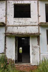A damaged entrance at a abandoned panel house with decorative facade of small white tiles.