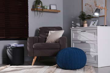 Stylish different poufs and armchair in room. Home design