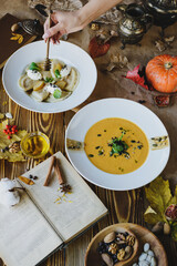 Autumn dishes: dumplings with walnuts, feta, honey and pear and pumpkin soup with seeds on a wooden table