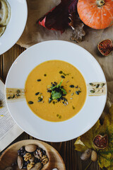 Autumn dishes: pumpkin soup with seeds on a textured wooden table