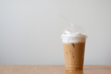 ice cappuccino in plastic cup on wooden table.  Copy space with white background.