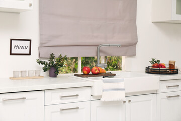 White kitchen interior with double bowl sink in front of window and fresh fruits