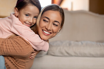 Portrait of happy woman and daughter hugging at home