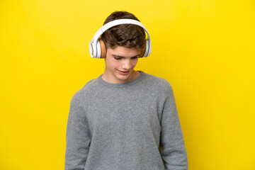 Teenager Russian man isolated on yellow background listening music