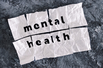 Mental health text on crumpled and torn piece of paper which has been reassembled with sticky tape, psychology and emotional healing