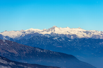 Mountain range of Monte Baldo (Baldo Mountain) in Adige Valley and National Park of Adamello Brenta with the peak of Care Alto seen from the Lessinia Plateau. Veneto and Trentino Alto Adige, Italy.