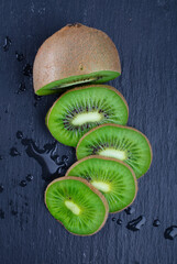 sliced ​​kiwi fruit on a black slate board background