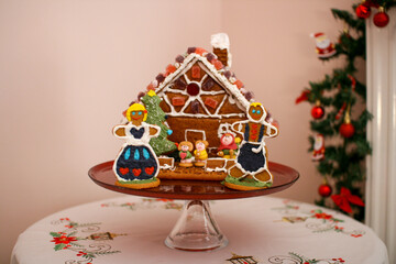 Gingerbread house decorated with a cookie family, candys on the roof and icing, on a plate during christmas