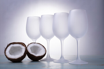 empty wine glasses on a table on a gray background next to a coconut