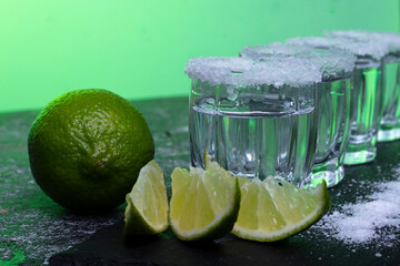 shot glasses with lime and ice on a dark table