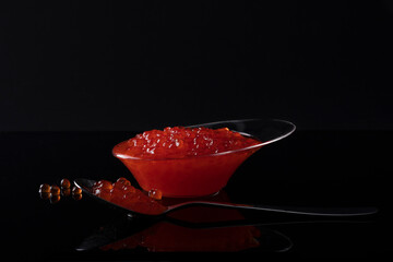 red caviar on a black background in a spoon and bowl
