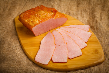 Fototapeta na wymiar sliced ​​boiled pork on a wooden board on a brown background