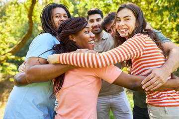 Group of young people stand in a circle and hug each other