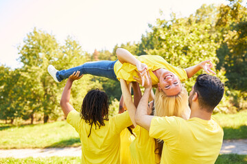 Obraz premium Young people lift up a laughing woman together