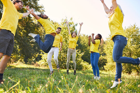 Group of young people jumping on meadow for team building