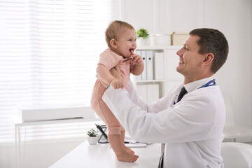 Pediatrician examining cute little baby in clinic