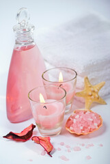 Spa composition in wellness center. Essential oil bottle, towels, candles, flower, seashells, and bath salt on white background.