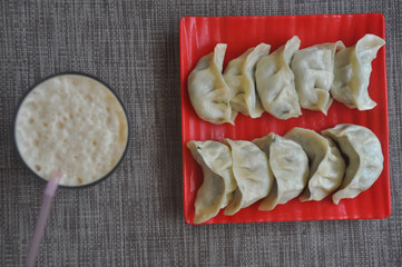 Overhead view of veg momos (Nepalese dumpling) with lassi over gray background 