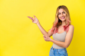 Young woman over isolated yellow background extending hands to the side for inviting to come