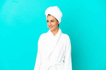 Young woman in a bathrobe over isolated blue background looking side