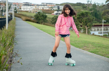 portrait of young child or teen girl roller skating outdoors, fitness, wellbeing, active healthy...