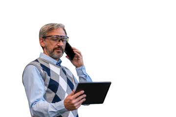 Mature Manager Looking At Digital Tablet Screen And Talking On Smartphone Isolated On White Background. Portrait Of Confident, Handsome, Gray-Haired Businessman. Man Standing And Using Smartphone.