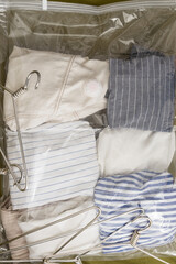 Vertical image of plastic vacuum bag for keeping apparel, empty hangers as background