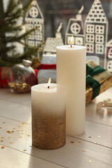 Fototapeta na wymiar Beautiful burning candles with Christmas decor on white wooden table near window