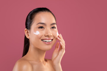 Beautiful chinese woman with moisturizer cream on her cheeks, closeup