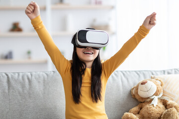 Emotional child teenager using VR glasses, raising hands up