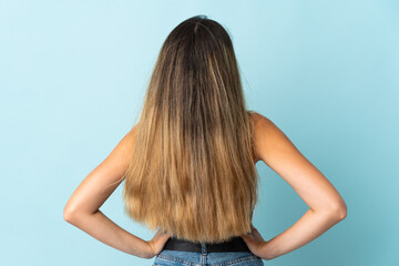 Young caucasian woman isolated on blue background in back position