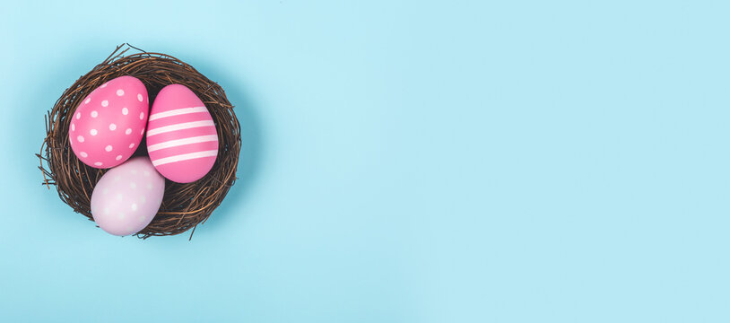 Happy easter banner. Blue Easter eggs in a nest on a pastel background