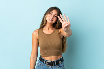 Young caucasian woman isolated on blue background happy and counting four with fingers