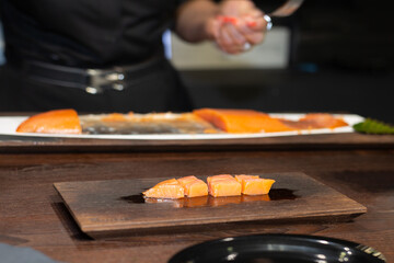 Chef Slicing Salmon on Black Wooden Table in a Restaurant