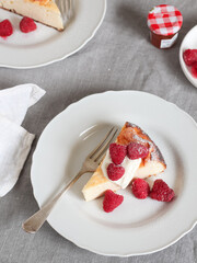 A slice of ricotta cake with frozen raspberries and cream on top for a weekend breakfast, flat lay style