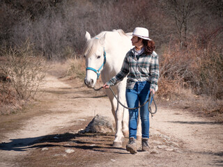 Female horse owner walking her white andalusian horse on a sunny autumn morning.