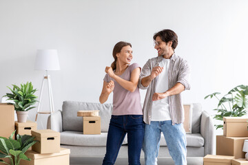 Fototapeta na wymiar Happy satisfied caucasian man and wife celebrating buying of new apartment, dancing in room interior