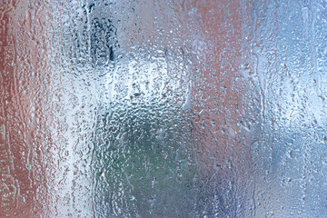 Blue background of natural water condensation, window glass with high air strong humidity, large drops drip. Collecting and streaming down