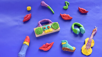 funny objects of the 90s made of plasticine tape recorder, microphone, guitar, lipstick, crayons on a bright purple background