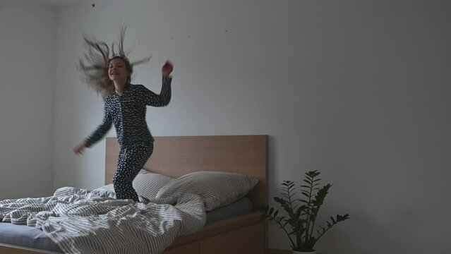 Happy teen child girl jumping fun in pajama on bed